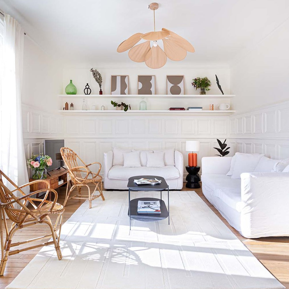 Le tapis blanc crème est mis en situation dans un grand salon. Le tapis made in france fait main. Le tapis est en laine couleur crème. Il y a un mélange de laine bouclée et laine velours ce qui lui donne un côté texturé, géométrique et contemporain.