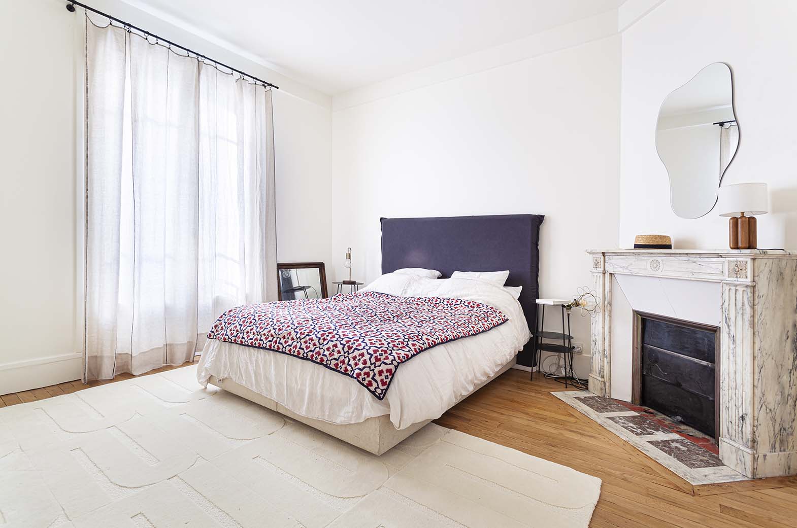Le tapis blanc crème est  mis en situation dans une chambre. Le tapis made in france fait main. Le tapis est en laine couleur crème. Il y a un mélange de laine bouclée et laine velours ce qui lui donne un côté texturé, géométrique et contemporain.